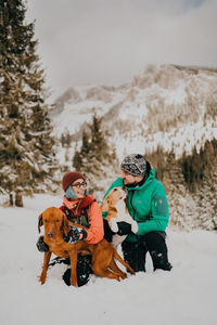 Portrait of couple with dogs on snow covered field