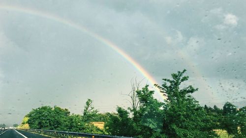 Scenic view of rainbow against sky during rainy season