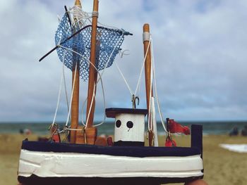 Close-up of sailboats on beach against sky