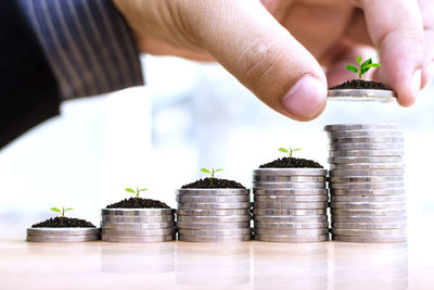 Cropped hand stacking coins with plants