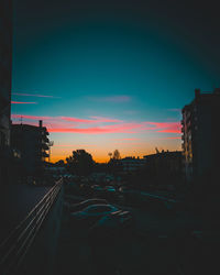 Cars on city against sky during sunset