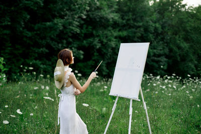 Full length of woman standing on field against trees