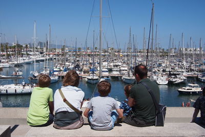 Rear view of family sitting against harbor