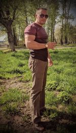 Young man wearing sunglasses standing on field