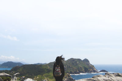 Woman standing by sea against sky