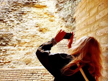 Midsection of woman holding umbrella against wall