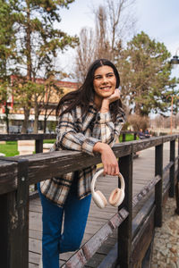 Portrait of smiling young woman sitting on railing