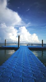 Pier on sea against blue sky