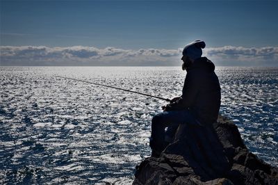 Man looking at sea against sky during winter