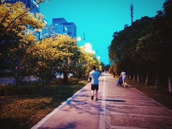 Rear view of people walking on sidewalk in city