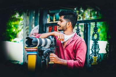 Side view of young man holding camera