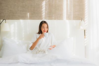 Portrait of a smiling young woman sitting on bed