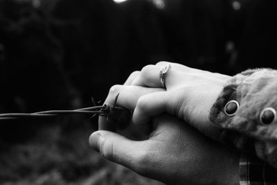 Cropped hands of couple holding fence