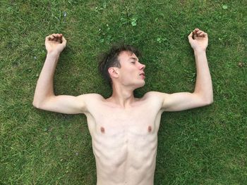 Young man lying on grassy field