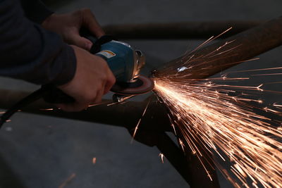 Cropped hands of male worker grinding metal in factory