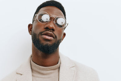 Portrait of young man wearing sunglasses against white background