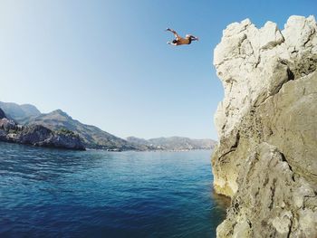 Man diving in lake against clear sky