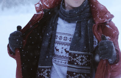 Midsection of mid adult man in warm clothing standing outdoors during snowfall