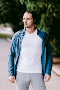 Handsome man listening music while standing in park