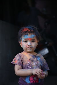 Portrait of cute girl face smeared with multicolored powder