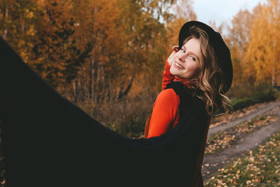 A pretty girl enjoys solitude drinks coffee walks in the autumn forest in nature in fall