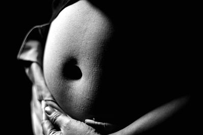 Close-up of pregnant woman's stomach against black background