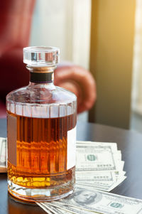 Close-up of hand holding glass bottle on table