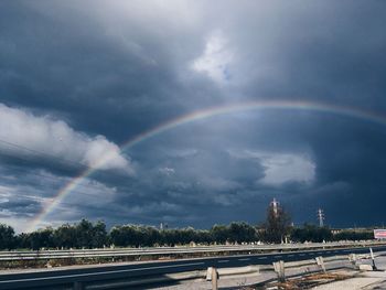 Rainbow over road in city against sky