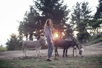 Portrait of woman with donkeys standing in farm