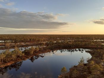 Scenic view of bog against sky during sunset