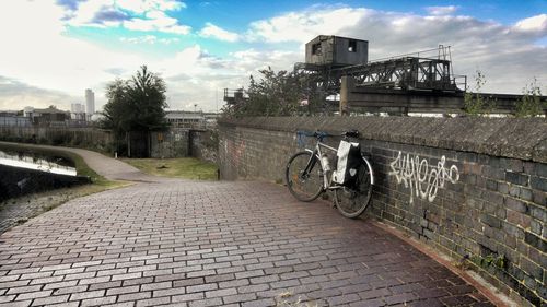 Bicycle on bridge in city against sky