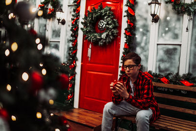 Full length of man sitting in illuminated christmas tree