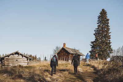 People hiking towards wooden cottages