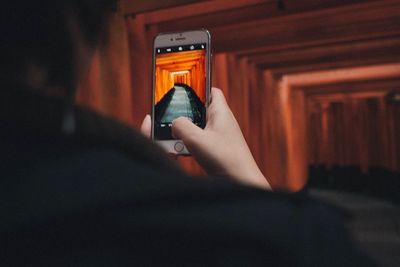 Rear view midsection of woman photographing torii gate