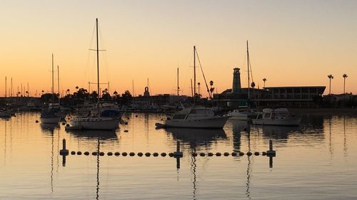 Boats moored at harbor during sunset