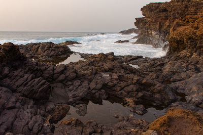 Scenic view of rocks on beach against sky