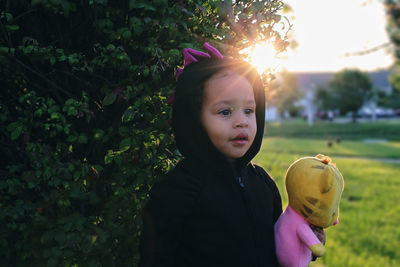 Portrait of boy holding apple against trees