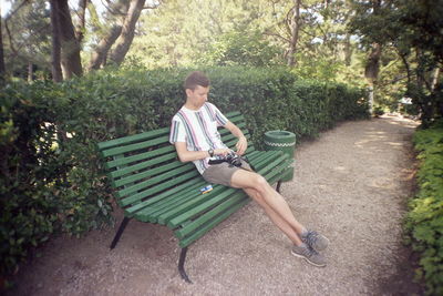 Boy sitting on bench in park