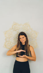 Portrait of young woman standing against wall