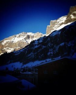 Scenic view of snow covered mountains against clear blue sky