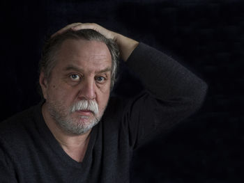 Close-up portrait of mature man against black background