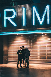 Full length of young man standing on illuminated road at night