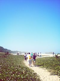 People on landscape against clear blue sky