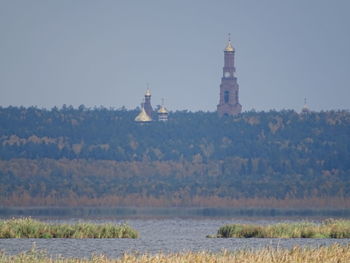 View of lighthouse by building against clear sky