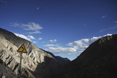 Road sign on mountain against blue sky