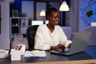 Smiling businesswoman working on laptop at office