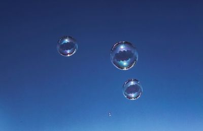 Low angle view of bubbles against blue sky