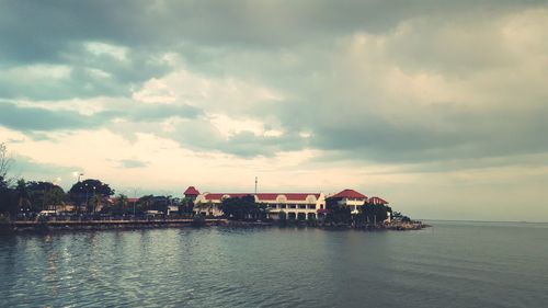 Houses by sea against sky in city