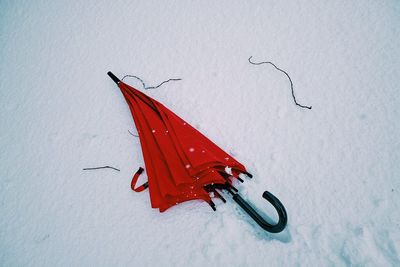 Red umbrella lying in snow