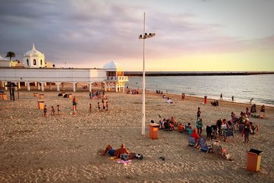 People at beach against sky during sunset